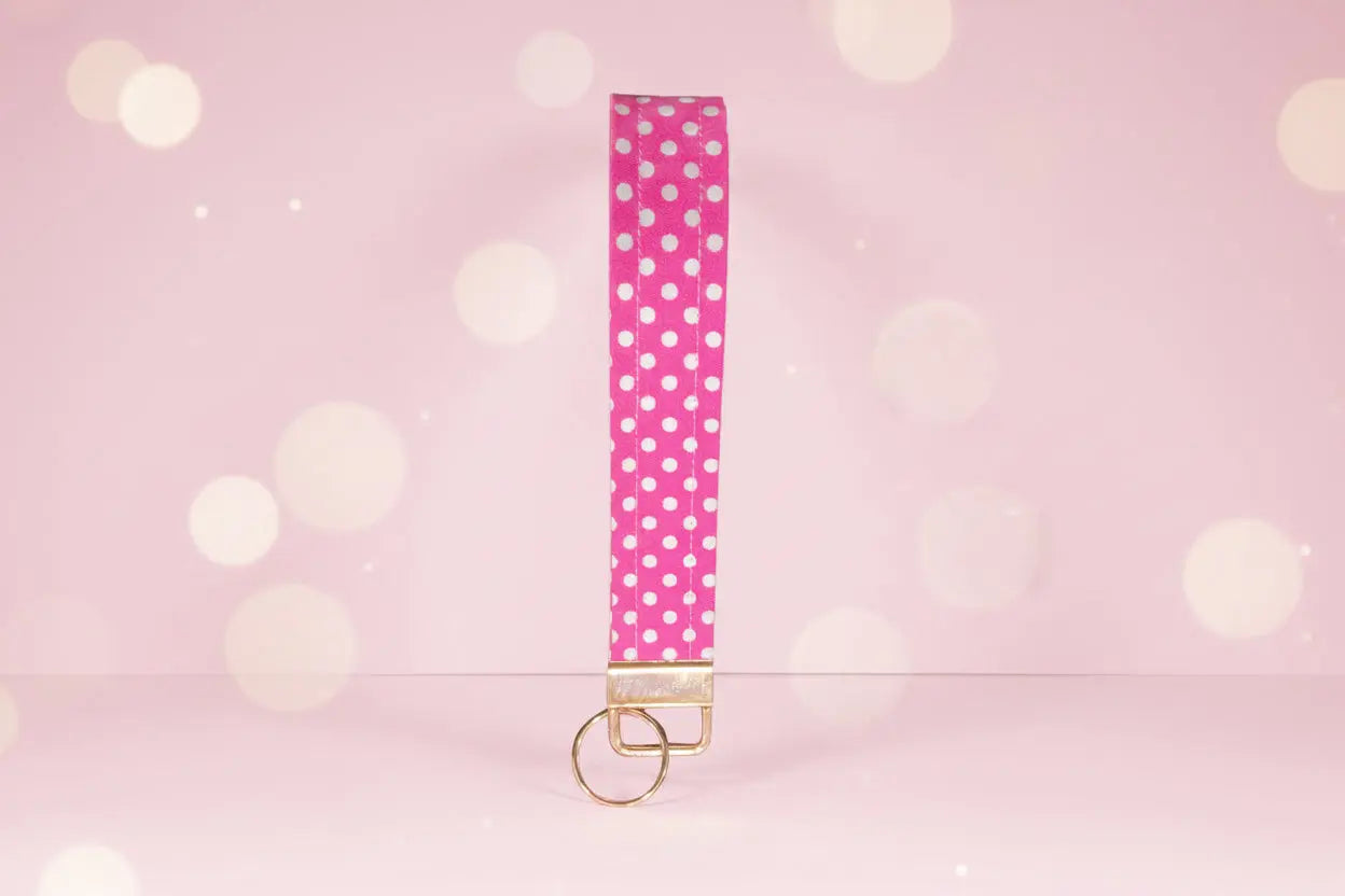 Pink keychain with white polka dots on a pink background